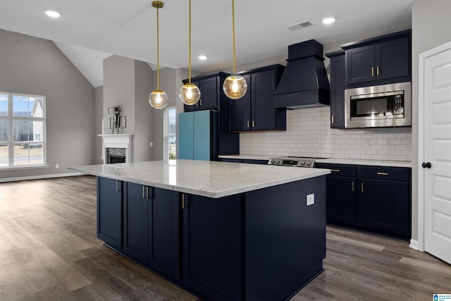 kitchen featuring a breakfast bar, appliances with stainless steel finishes, a center island, decorative light fixtures, and custom exhaust hood