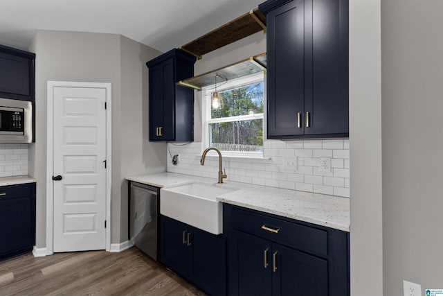 kitchen featuring sink, stainless steel microwave, dark hardwood / wood-style flooring, light stone countertops, and decorative backsplash