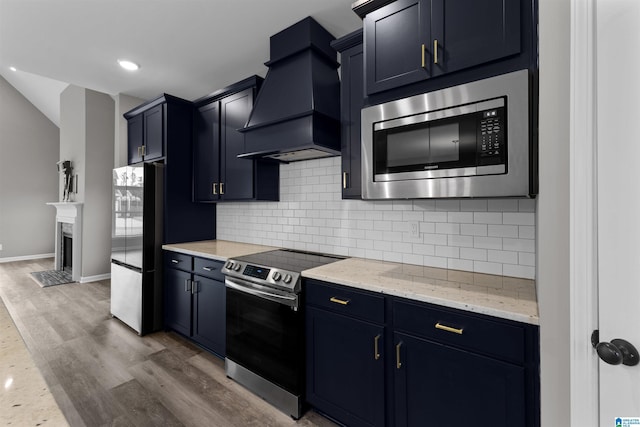 kitchen featuring appliances with stainless steel finishes, custom range hood, hardwood / wood-style floors, and backsplash