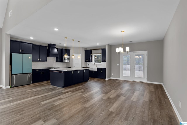 kitchen with a center island, hanging light fixtures, custom range hood, and refrigerator