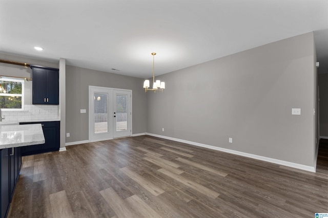 unfurnished dining area featuring dark hardwood / wood-style floors, a notable chandelier, and french doors