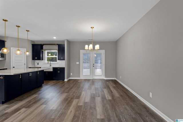 kitchen featuring dark wood-type flooring, hanging light fixtures, tasteful backsplash, french doors, and a chandelier