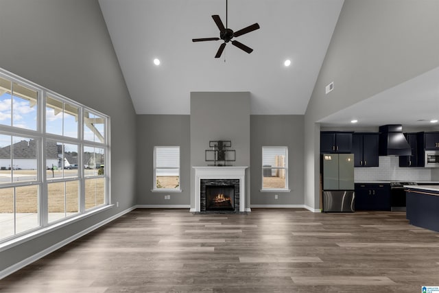 unfurnished living room featuring dark wood-type flooring, high vaulted ceiling, a premium fireplace, and ceiling fan