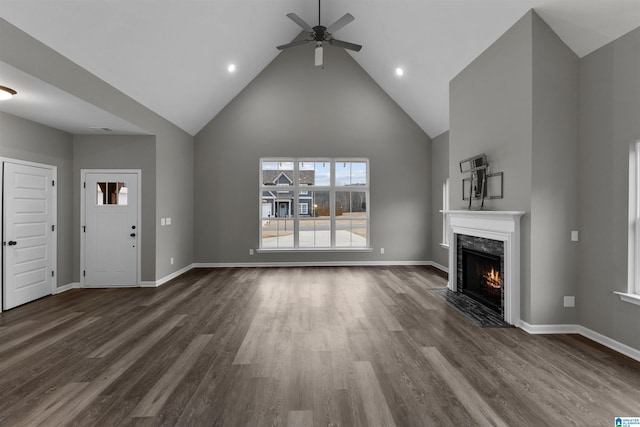 unfurnished living room with dark hardwood / wood-style flooring, high vaulted ceiling, a premium fireplace, and ceiling fan