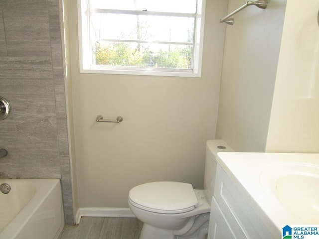 full bathroom with hardwood / wood-style flooring, tiled shower / bath, vanity, and toilet