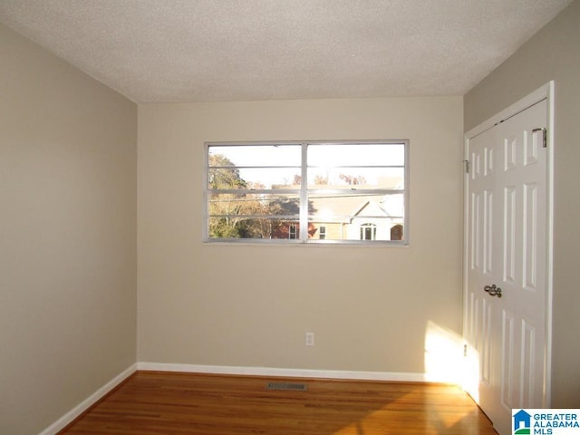 spare room featuring hardwood / wood-style flooring and a textured ceiling