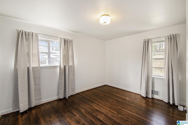 unfurnished bedroom with dark wood-style floors, baseboards, and visible vents