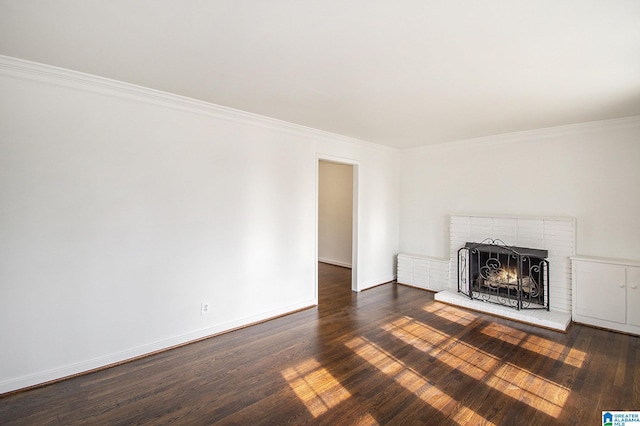 unfurnished living room with crown molding, a brick fireplace, dark wood finished floors, and baseboards