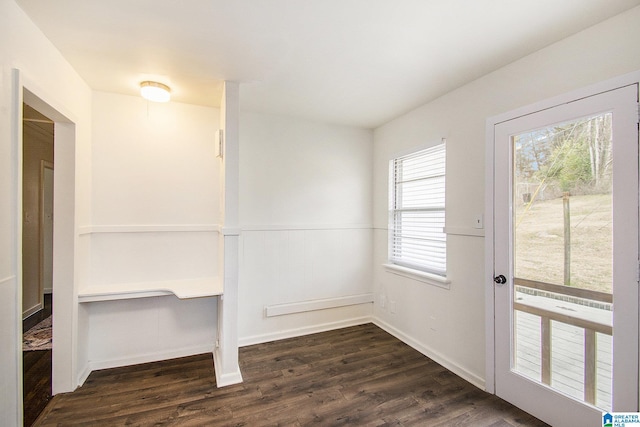 doorway with a wainscoted wall and dark wood finished floors