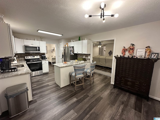 kitchen featuring light stone countertops, white cabinetry, appliances with stainless steel finishes, and a kitchen bar