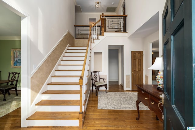 foyer featuring dark hardwood / wood-style flooring, a towering ceiling, and ornamental molding