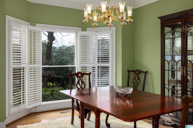 dining space featuring a notable chandelier, ornamental molding, and light hardwood / wood-style floors