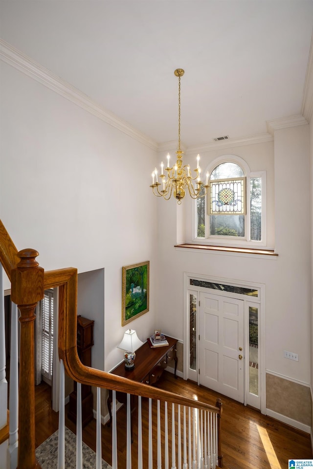 foyer with ornamental molding, dark hardwood / wood-style floors, and an inviting chandelier