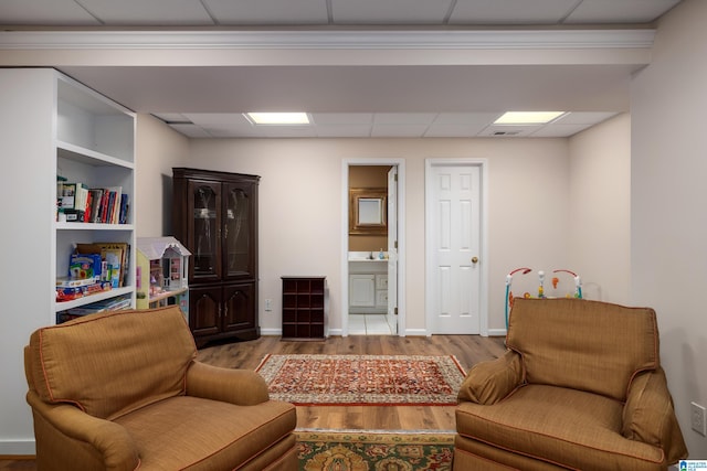 living area featuring a paneled ceiling and light hardwood / wood-style floors