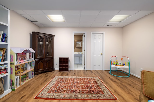 recreation room with a drop ceiling and light wood-type flooring