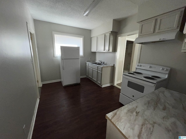 kitchen featuring sink, white appliances, dark hardwood / wood-style floors, and a textured ceiling