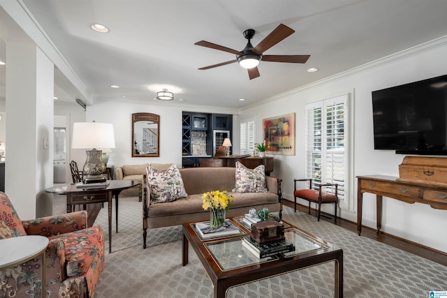 living room with ornamental molding, wood-type flooring, and ceiling fan