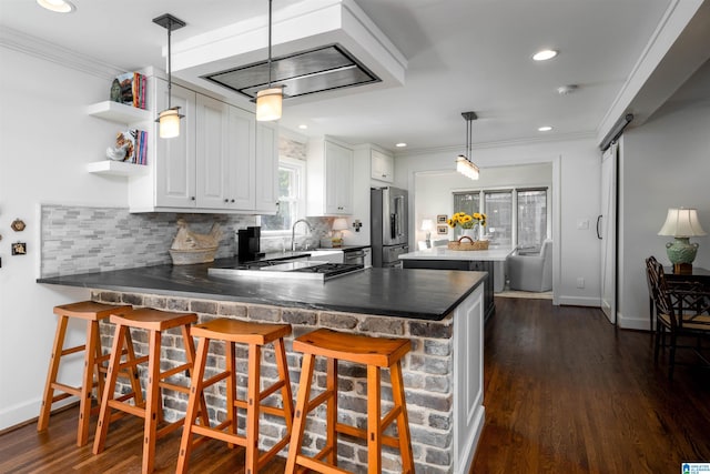 kitchen featuring high end refrigerator, kitchen peninsula, pendant lighting, a barn door, and white cabinets