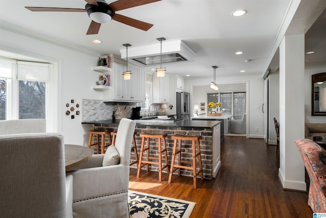 kitchen featuring white cabinetry, high quality fridge, a kitchen breakfast bar, kitchen peninsula, and a barn door