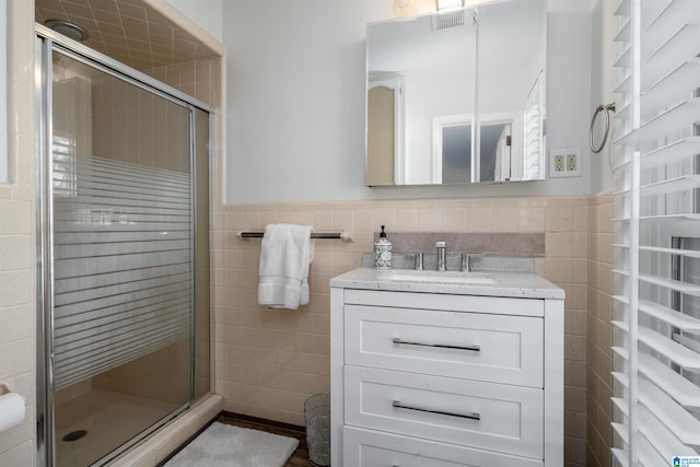 bathroom with tile walls, vanity, and a shower with shower door