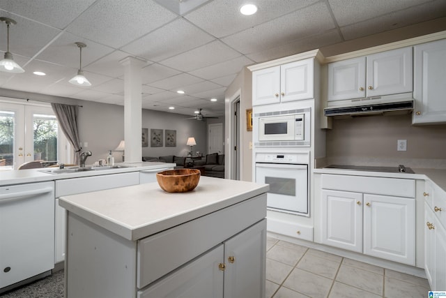 kitchen with pendant lighting, sink, white appliances, a paneled ceiling, and white cabinetry