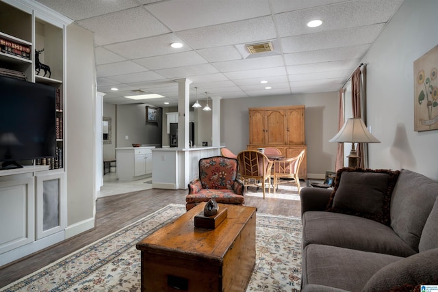 living room with wood-type flooring and a drop ceiling