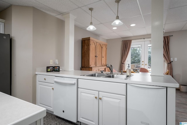 kitchen with decorative light fixtures, sink, white cabinets, white dishwasher, and kitchen peninsula