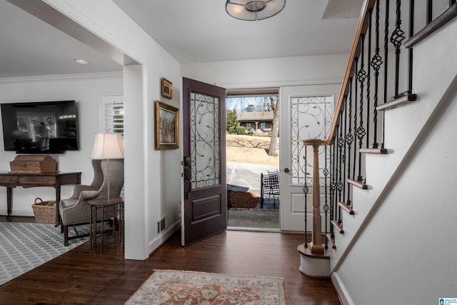 foyer with dark wood-type flooring and crown molding