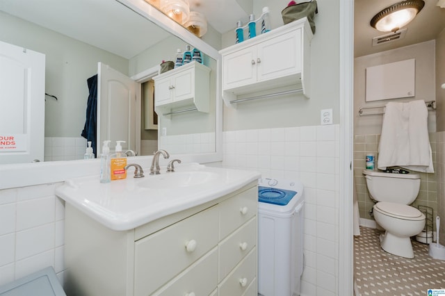 bathroom featuring vanity, tile walls, and toilet