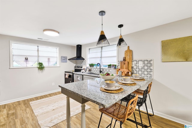 kitchen with stainless steel range with electric stovetop, wall chimney exhaust hood, sink, and plenty of natural light