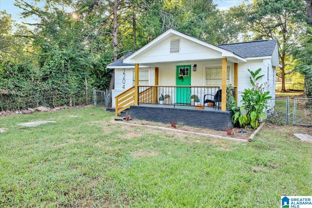 rear view of house featuring a lawn and covered porch