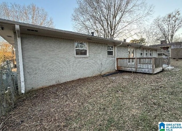 rear view of house with brick siding and a deck