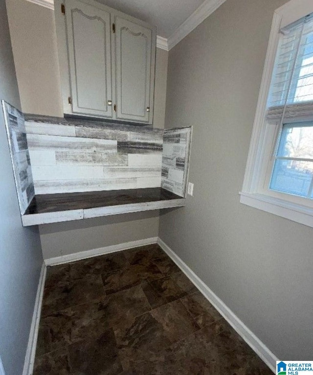 interior space with crown molding, tasteful backsplash, and baseboards