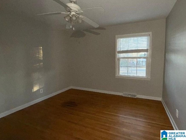 empty room featuring visible vents, baseboards, dark wood finished floors, and a ceiling fan