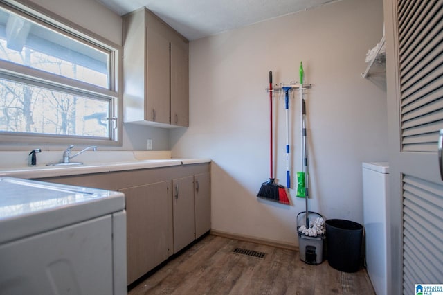 laundry area with cabinets and light wood-type flooring