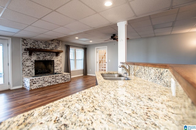 unfurnished living room featuring sink, dark wood-type flooring, a fireplace, and ceiling fan