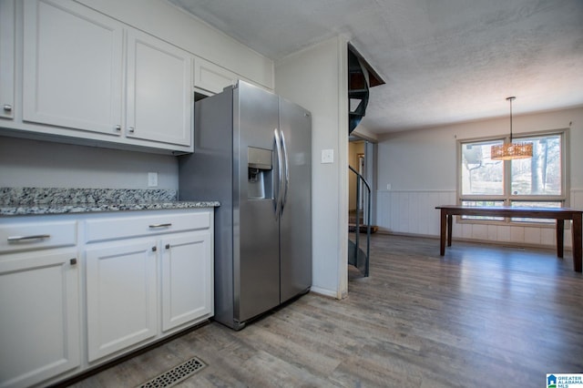 kitchen featuring stainless steel fridge, white cabinetry, hanging light fixtures, a textured ceiling, and light wood-type flooring