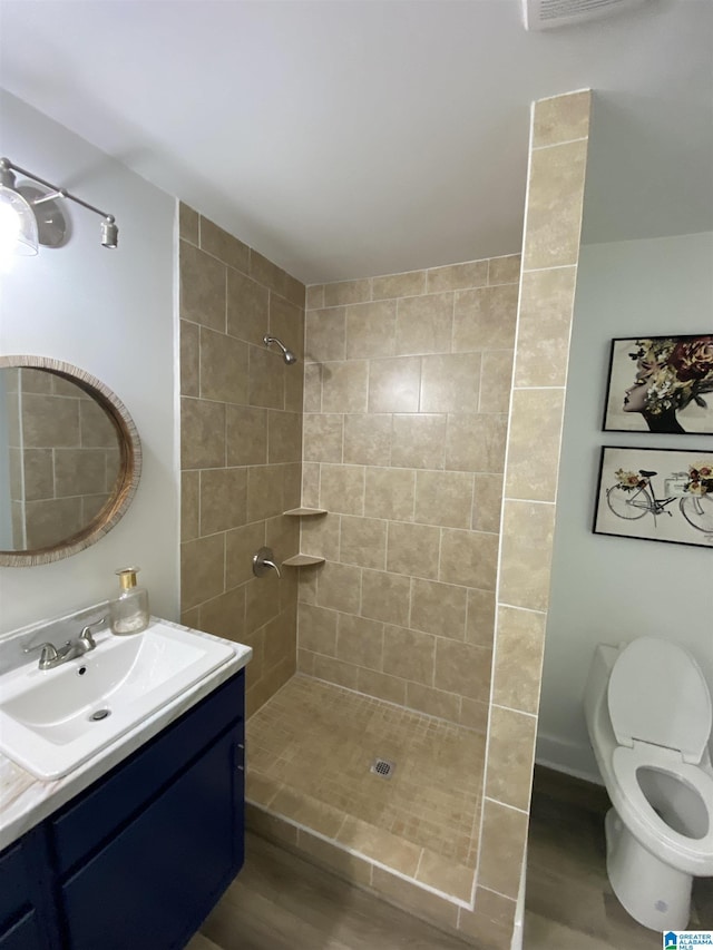 bathroom with vanity, a tile shower, and toilet