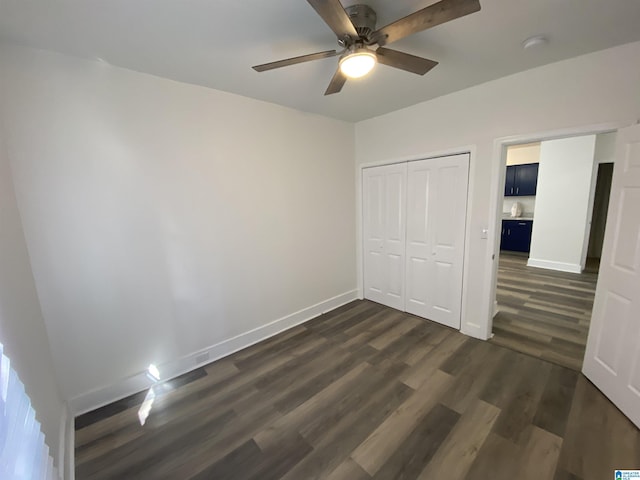 unfurnished bedroom with ceiling fan, a closet, and dark wood-type flooring