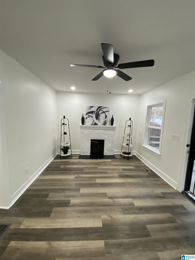 exercise room featuring a fireplace, dark wood-type flooring, and ceiling fan