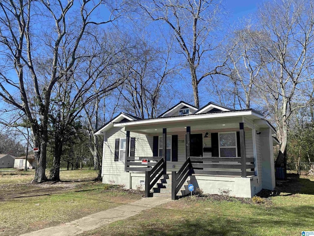 bungalow-style house featuring covered porch and a front yard