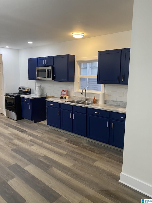 kitchen with hardwood / wood-style floors, blue cabinetry, appliances with stainless steel finishes, and sink