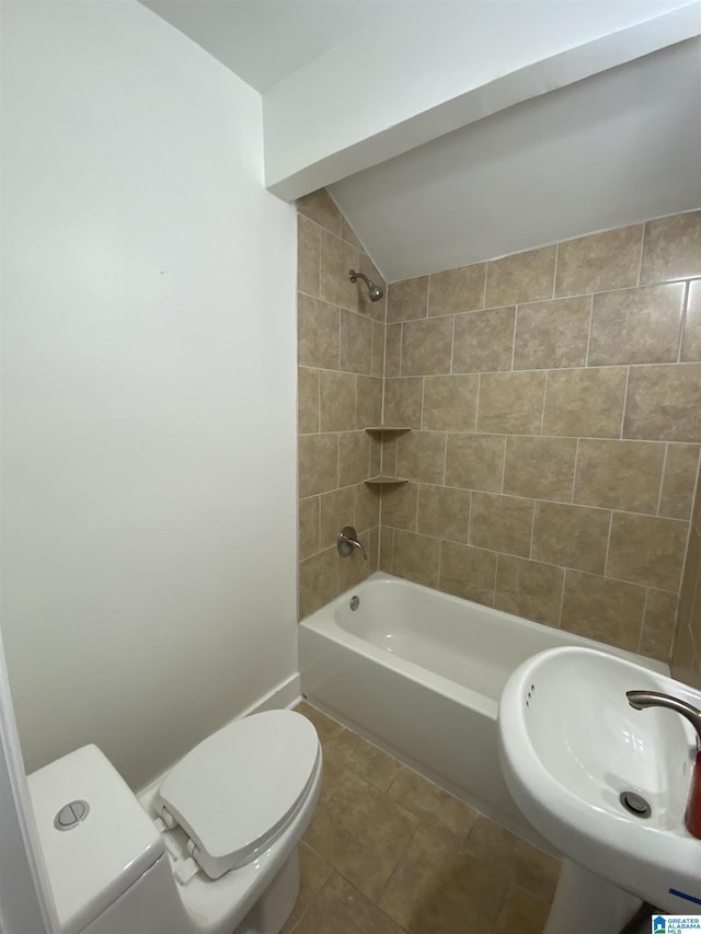 full bathroom featuring tile patterned flooring, sink, toilet, vaulted ceiling, and tiled shower / bath combo