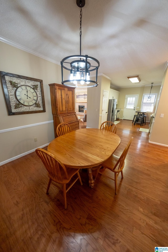 dining area featuring hardwood / wood-style floors, crown molding, a chandelier, and a textured ceiling