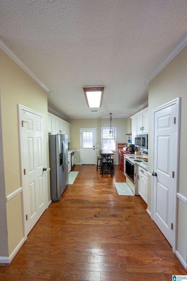 kitchen with white cabinetry, appliances with stainless steel finishes, dark hardwood / wood-style floors, and hanging light fixtures