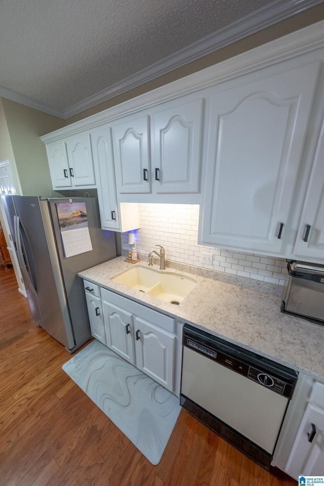 kitchen with sink, stainless steel fridge, white cabinetry, white dishwasher, and ornamental molding