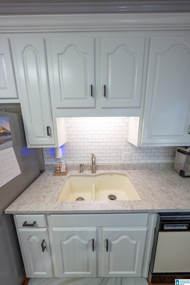 kitchen with sink, backsplash, white cabinets, white dishwasher, and light stone countertops