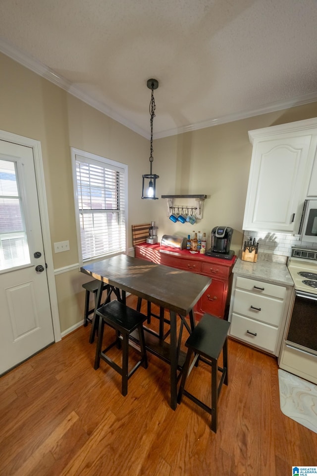 dining space featuring ornamental molding, a healthy amount of sunlight, and light hardwood / wood-style floors