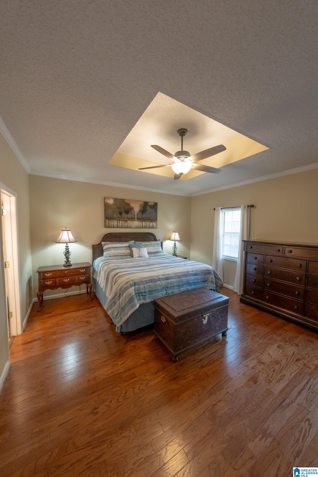 bedroom with hardwood / wood-style floors, crown molding, a raised ceiling, and a textured ceiling