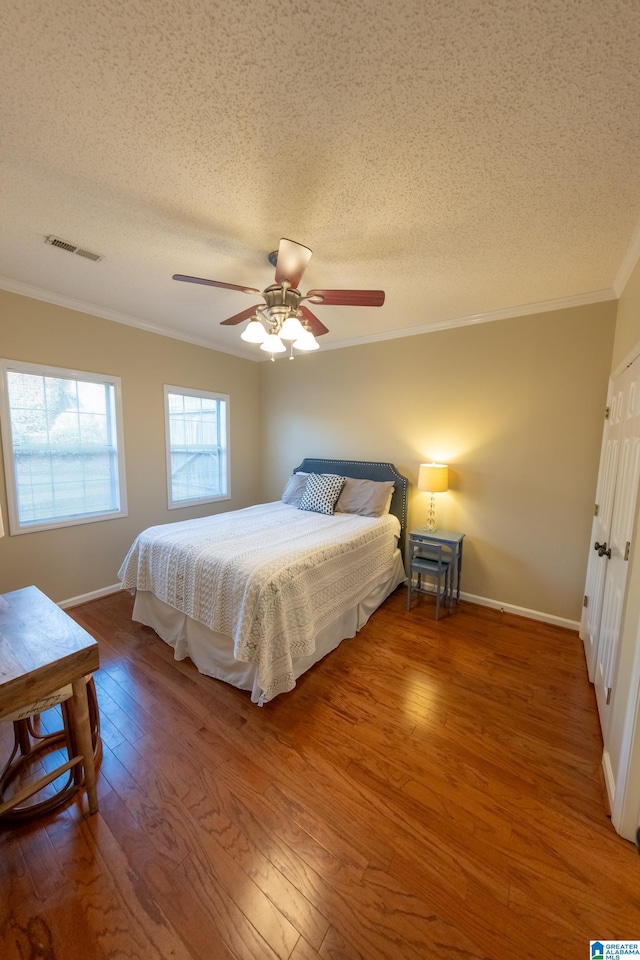 bedroom featuring crown molding, hardwood / wood-style floors, ceiling fan, and a textured ceiling